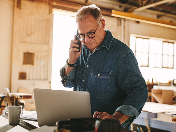 Business owner on phone and using laptop implying a home service business executing a custom marketing strategy.