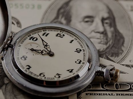 Watch resting on hundred-dollar bills representing time and money savings from lead generating websites.